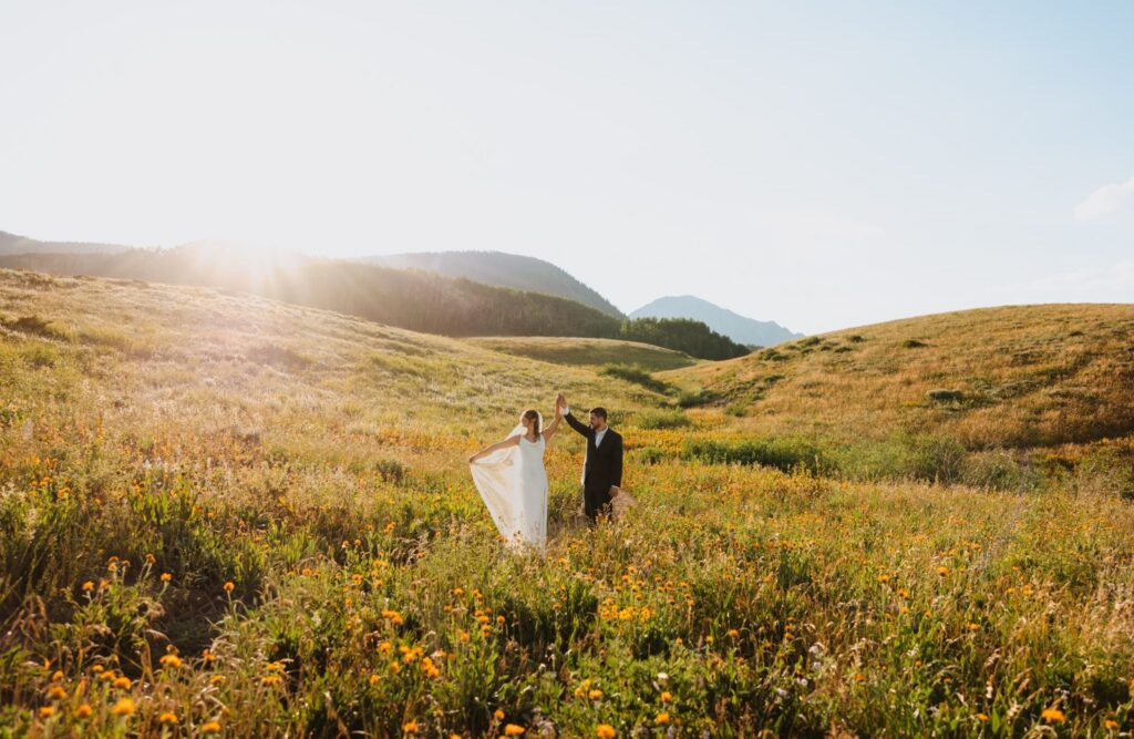 Groom spinning bride among yellow wildflowers for Crested Butte wildflower elopement.