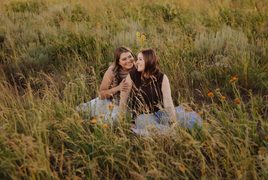Lesbian couple poses side by side among wildflowers during Crested Butte engagement.