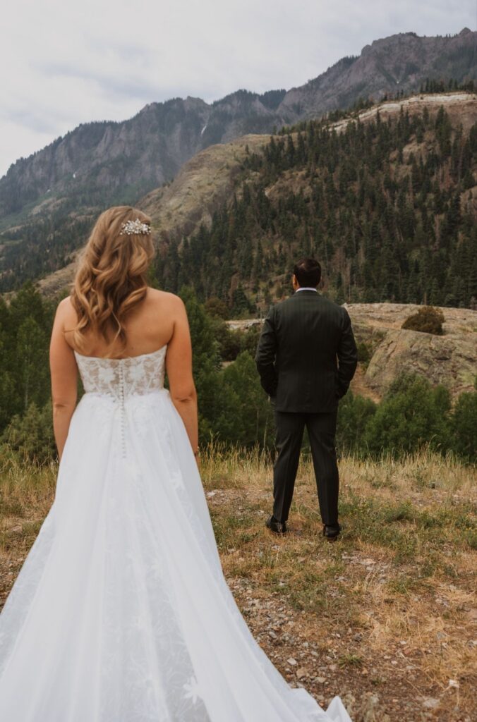 Moment before a first look with a groom and bride on a mountain side.