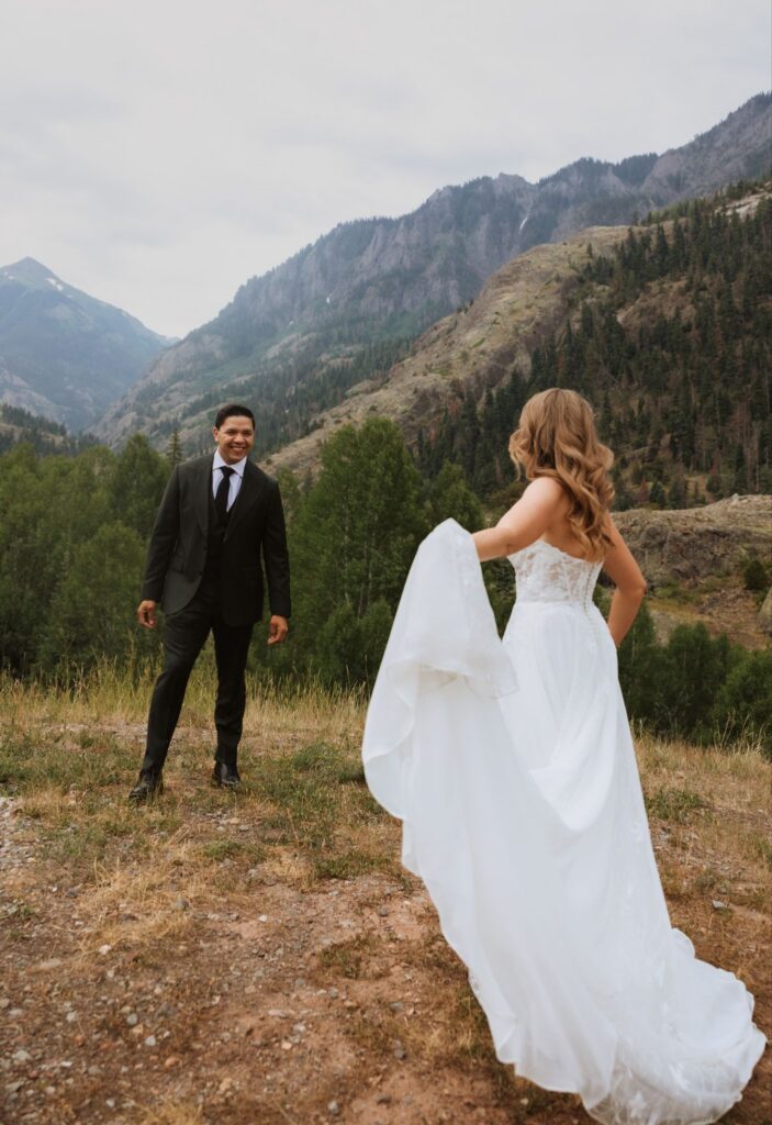 Groom smiling at bride during first look on mountainside for a Gold Mountain Ranch wedding.