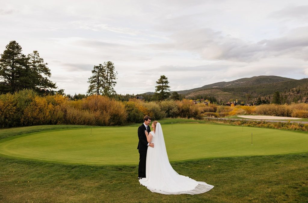 Bride and groom embrace on golf green in Loveland Pass elopement.