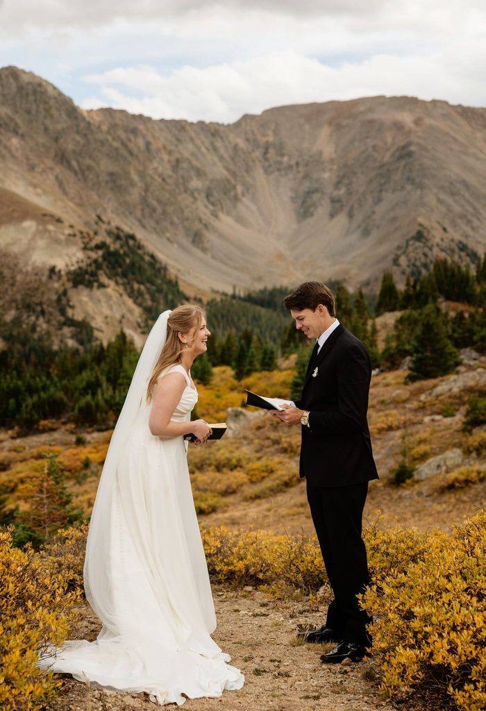Bride and groom exchange vows with bride laughing with mountains in the background of a Loveland Pass elopement.